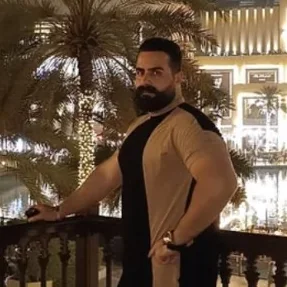 Reza Shams on a balcony at night, with palm trees and the Dubai skyline behind him